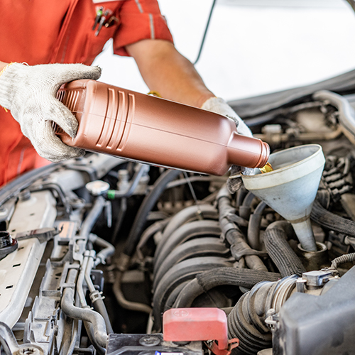 Car mechanic replacing and pouring fresh oil